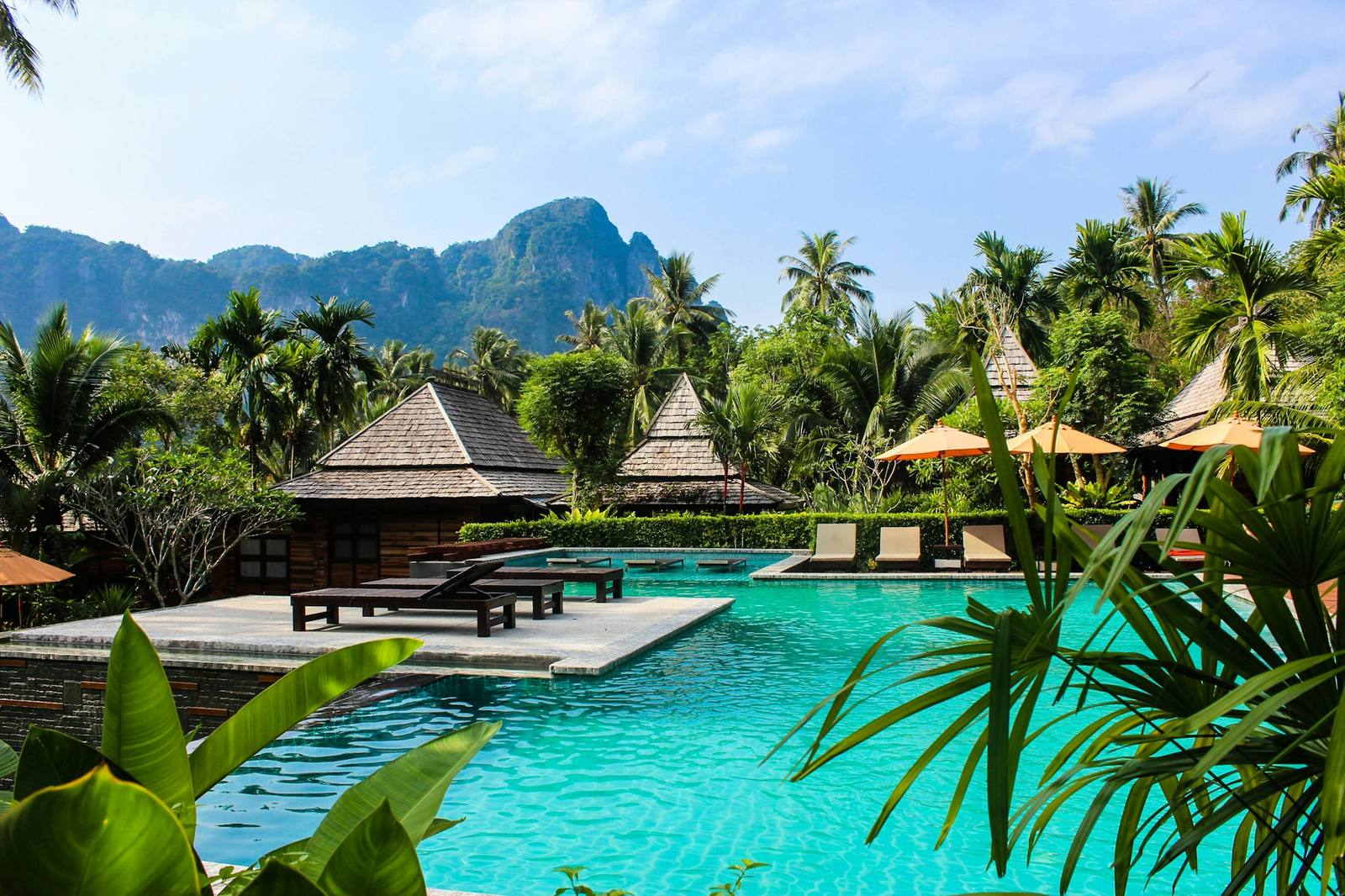 Thatched-roof villas beside a pool at a boutique tropical resort